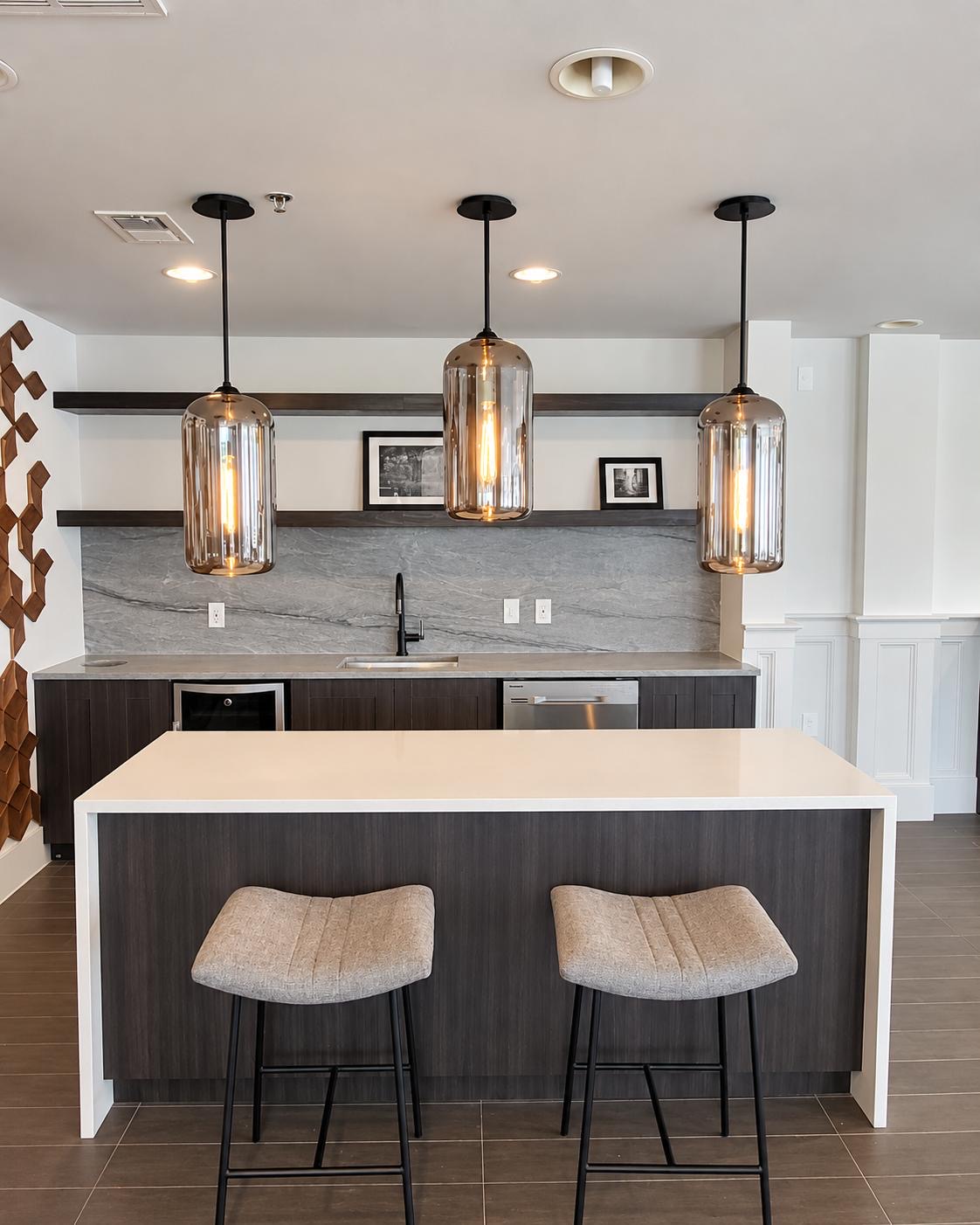 Contemporary kitchen with white island, two stools, and glass pendant lighting