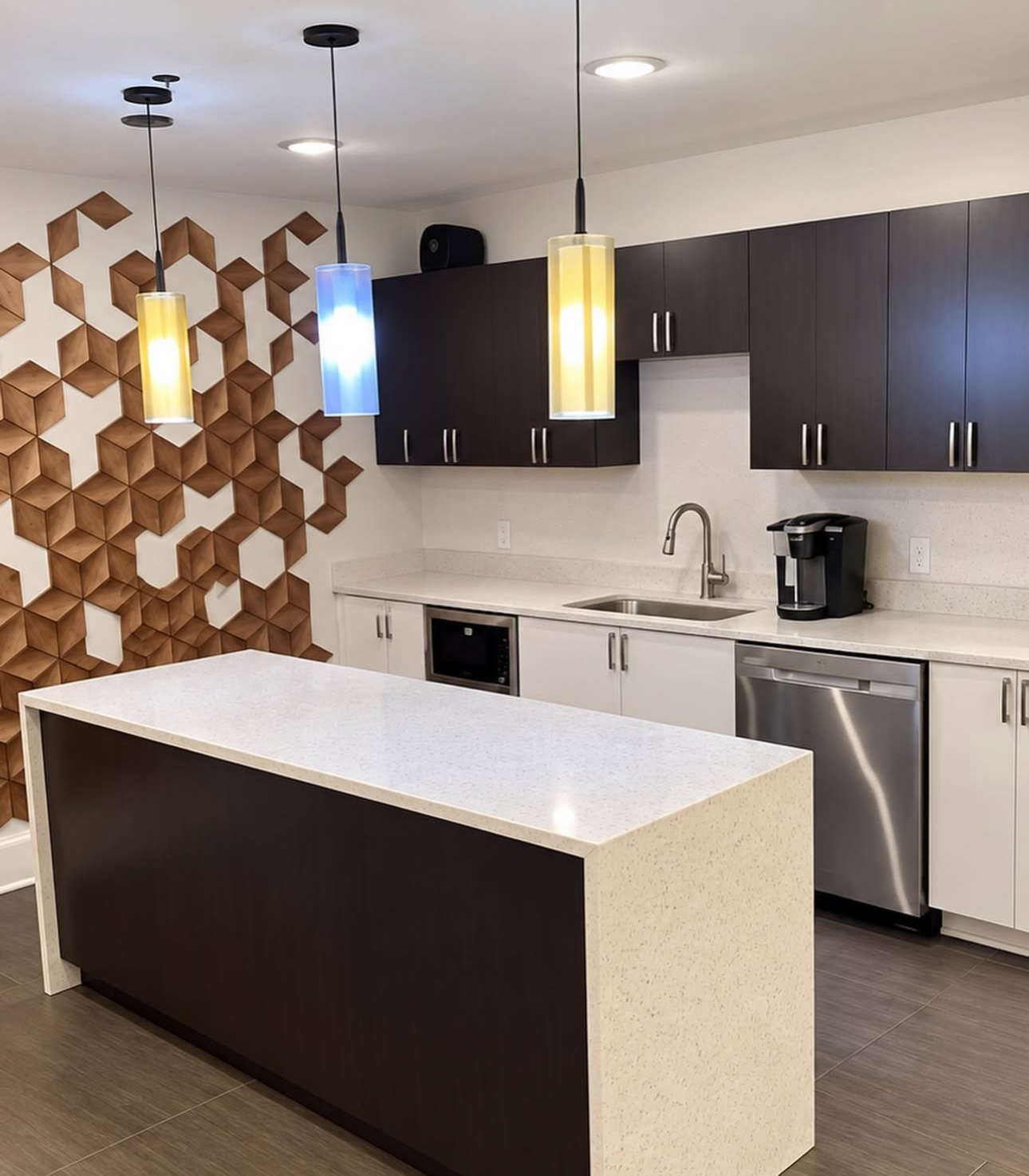 Kitchen with waterfall island, geometric wood accent wall, and pendant lighting